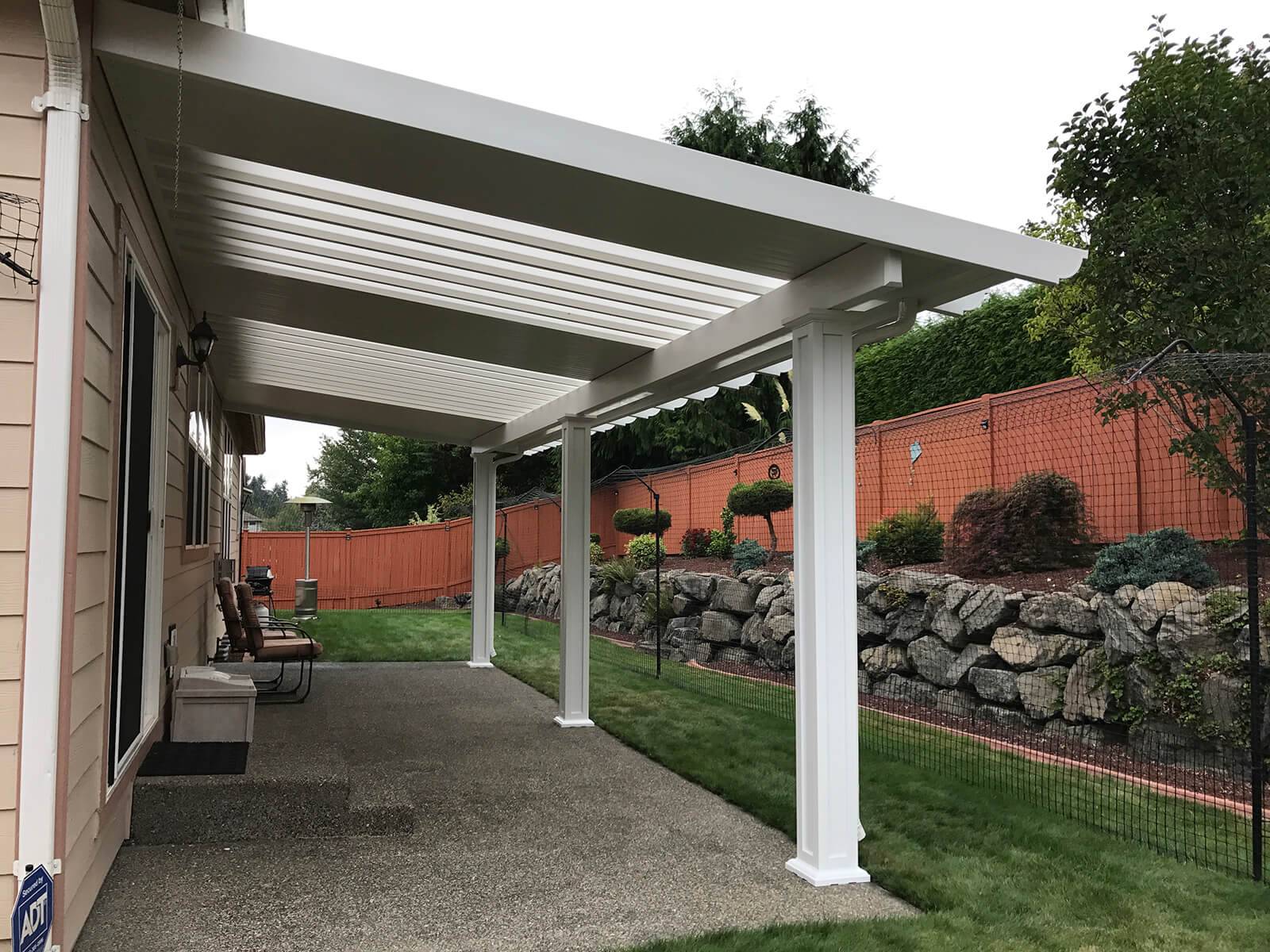 A covered patio featuring a white roof and stone walls, providing a cozy outdoor space for relaxation.