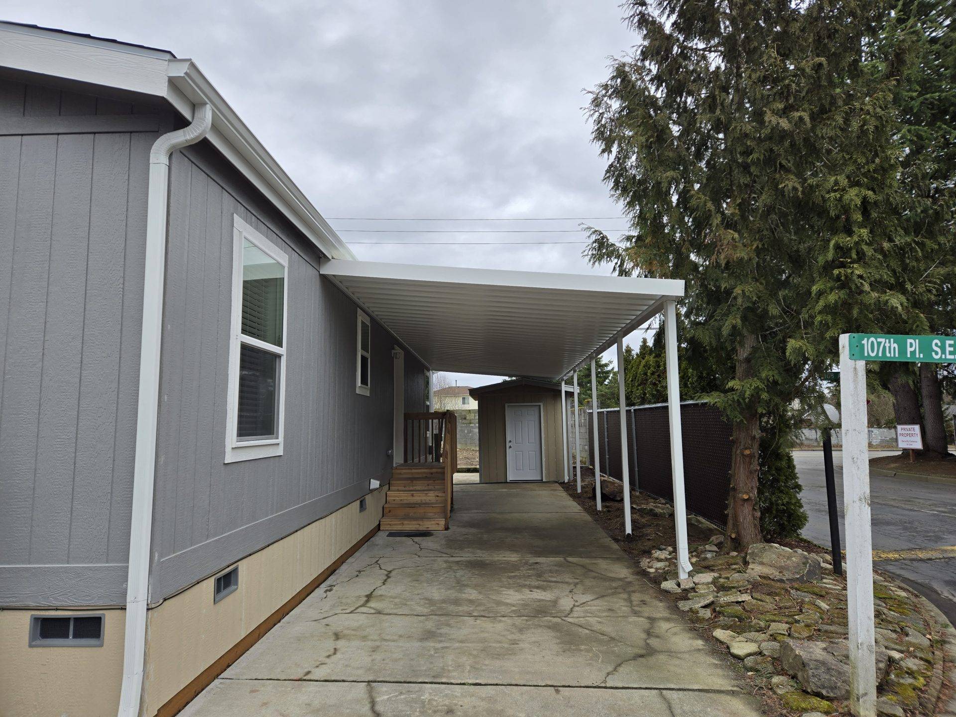 A gray house featuring a covered porch and a sidewalk leading to the entrance.
