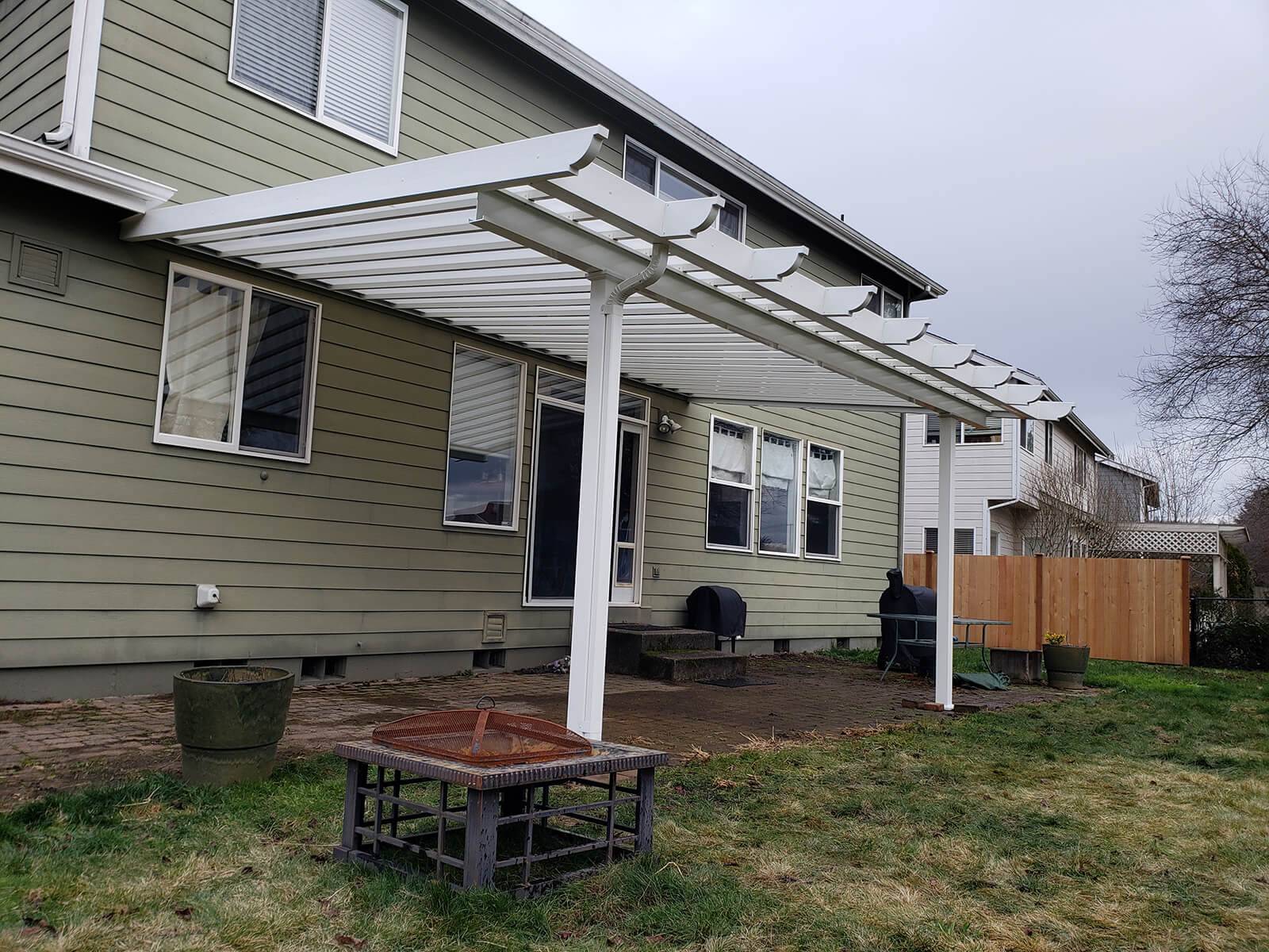 A house featuring a patio cover with a white roof, providing shade and shelter for outdoor activities.